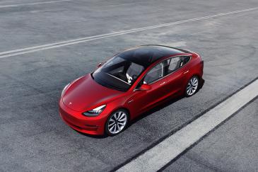 Prijs van Tesla model 3 Rode Tesla model 3 op de weg