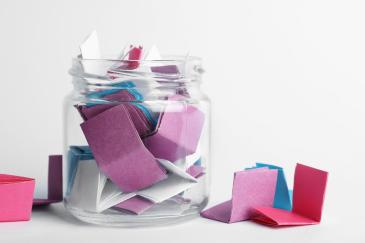 Glazen pot vol gekleurde briefjes met anti-verveel tips