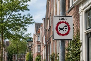 Verkeersbord voor een milieuzone in een straat met woningen en bomen.