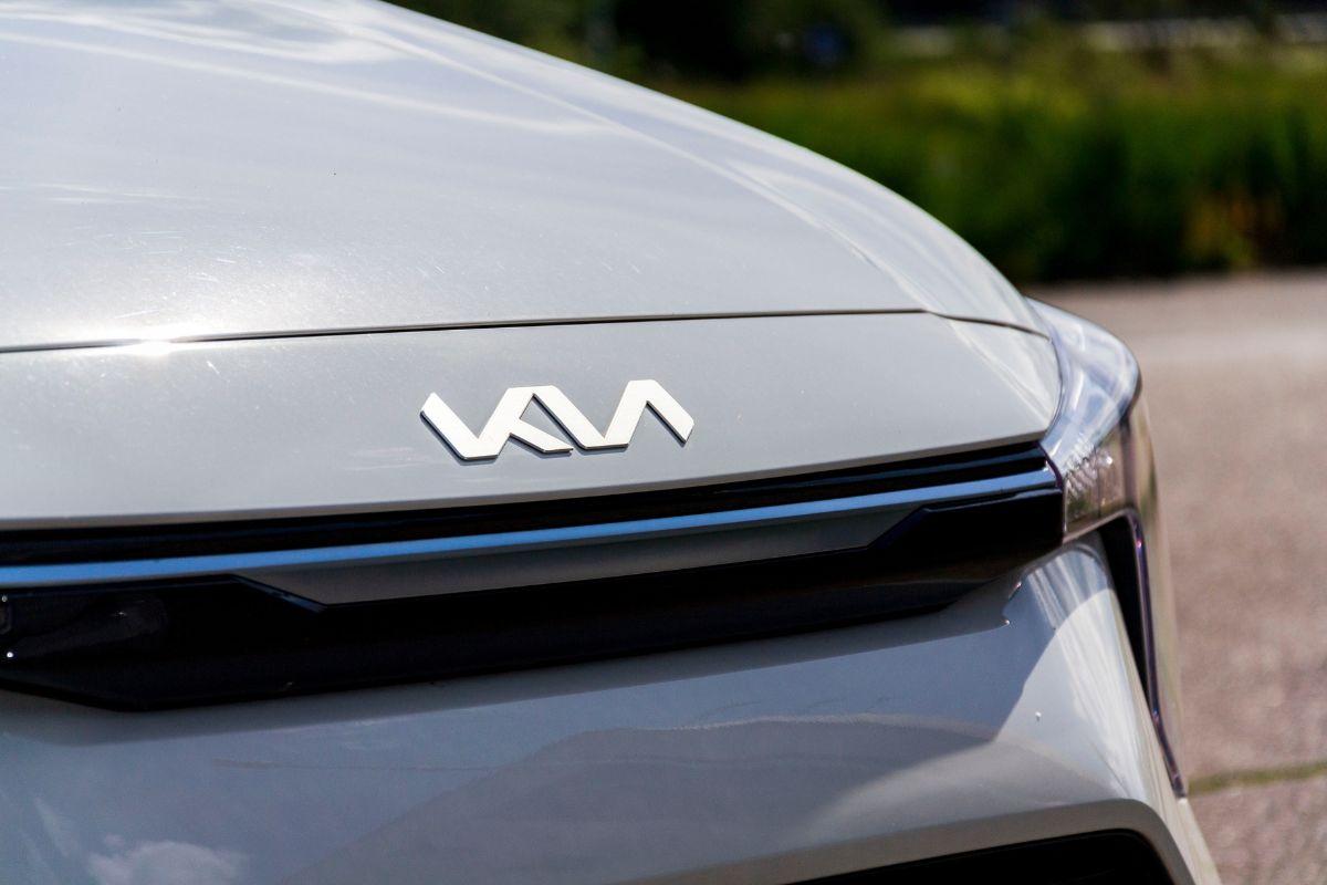 Close-up van de voorkant van een zilverkleurige auto met het moderne Kia-logo op de motorkap.