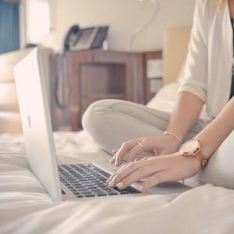 sluit opstal en inboedelverzekering samen af vrouw op bed met laptop