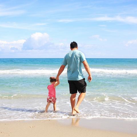 Vader en dochter op strand in het water