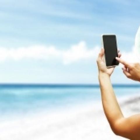 Vrouw maakt foto met smartphone op wit strand