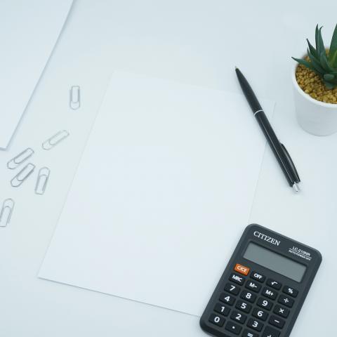 Calculator op een wit bureau met plant