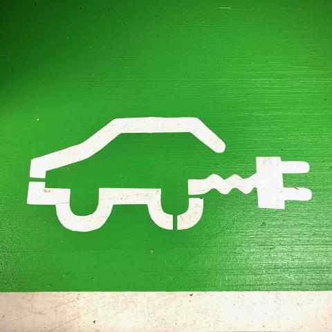 Groene muur met wit logo van elektrische auto met stekker