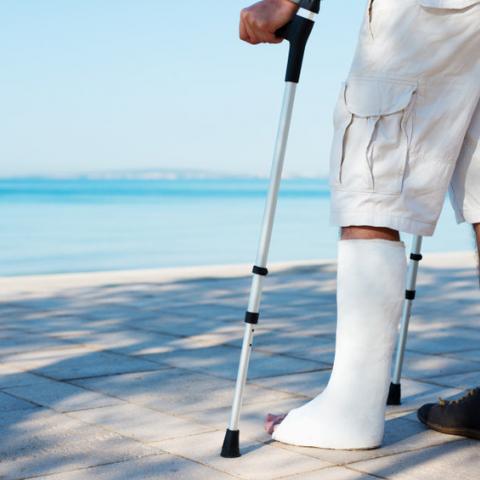 man met been in gips aan zee in buitenland