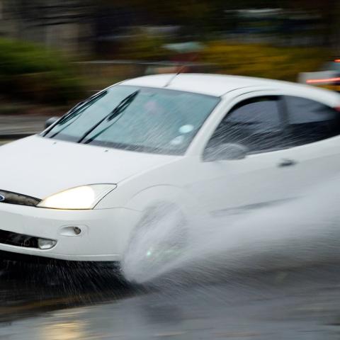 Auto rijdt op een nat wegdek door spoorvorming