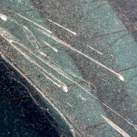 Ruit van een auto die bedekt is met zand
