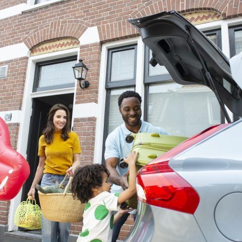 een gezin stopt bagage in de auto