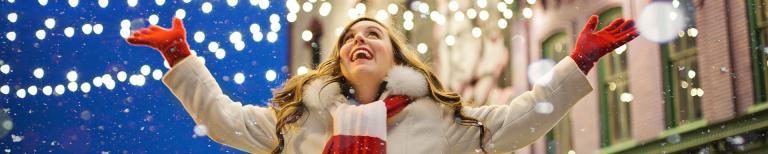 Wanneer is het kerstvakantie in Noord, Midden en Zuid Nederland? Vrouw met kerstlichtjes en sneeuw