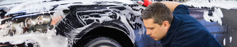 Auto wassen? Voorkom deze veelgemaakte fouten Man wast de auto